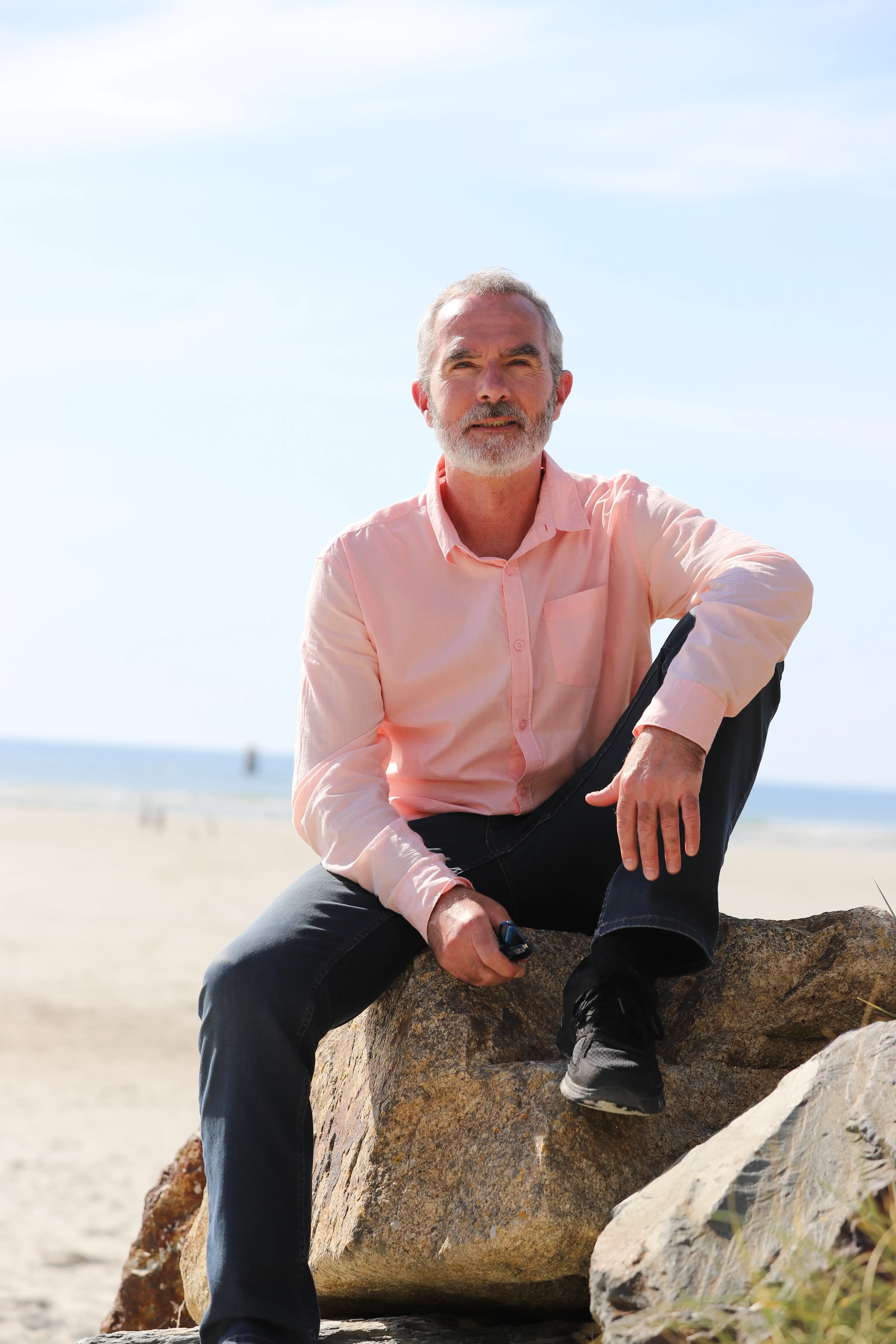 Gwenaël Petton, assis sur un rocher face à la mer